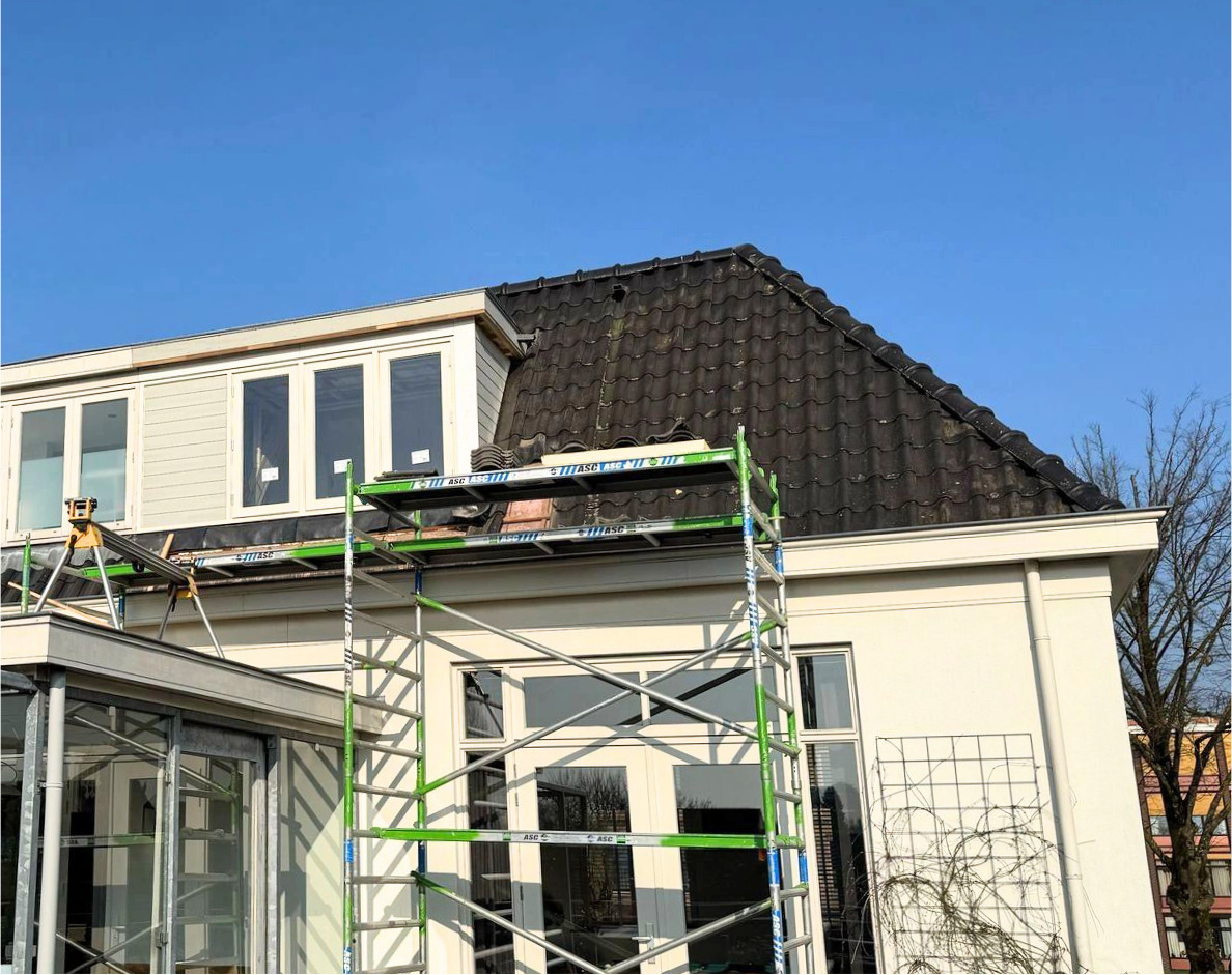 Bouwfase dakkapel, aanzicht woning met steigers en dakwerkers in uitvoering